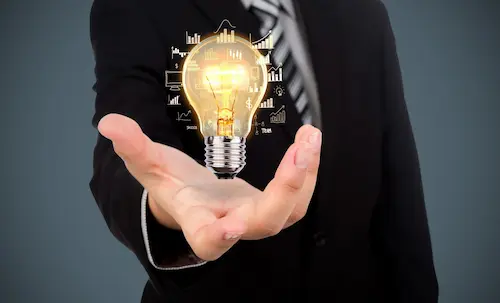 Glowing light bulb with growth charts held in an open hand