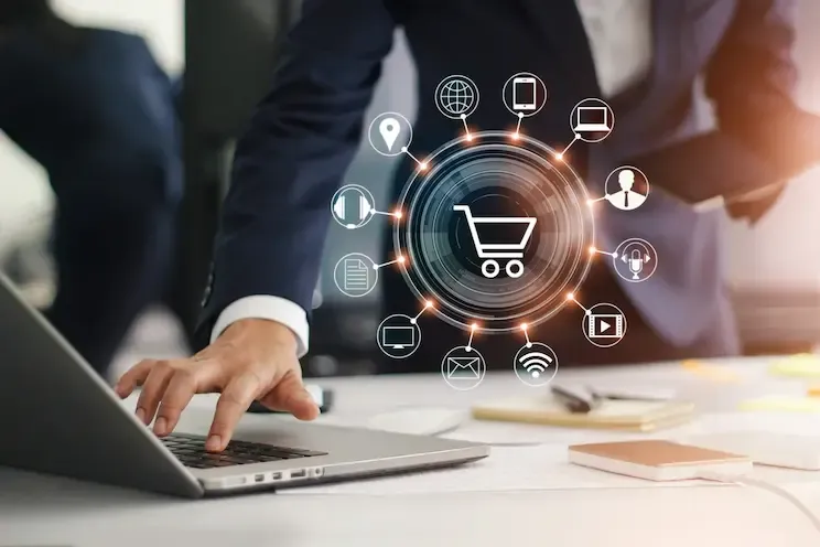 Developer working on a laptop with ecommerce and digital service icons around a shopping cart