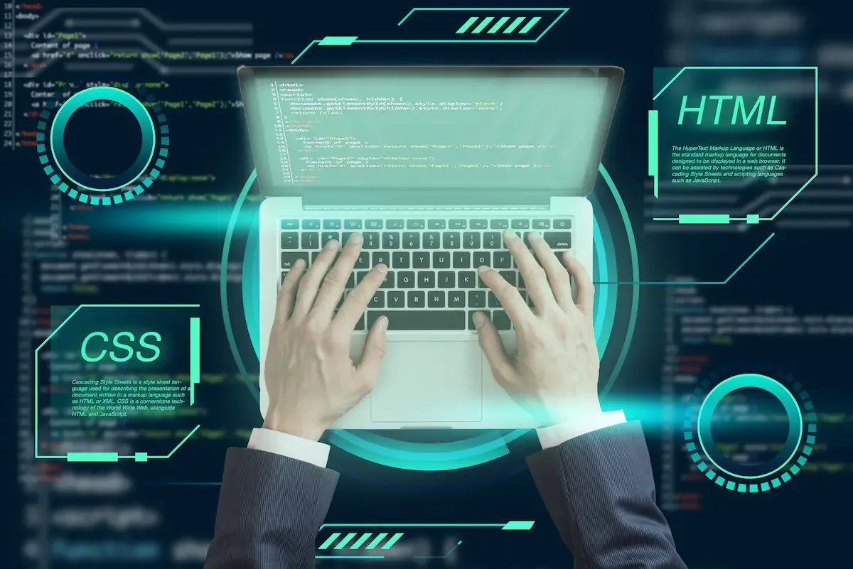 Hands typing on a laptop beneath glowing HTML and CSS panels